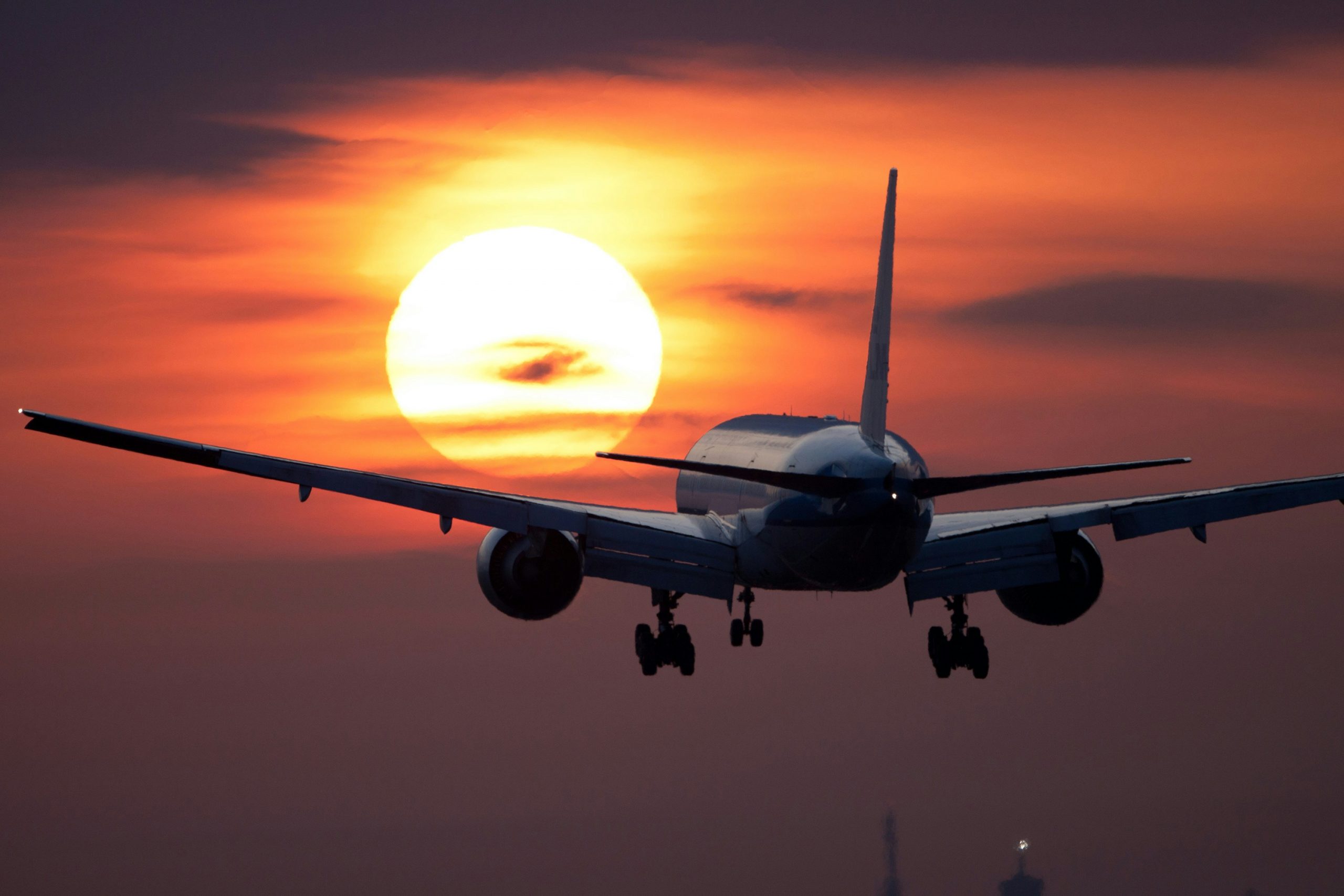 Airliner flying over a fiery orange sunset